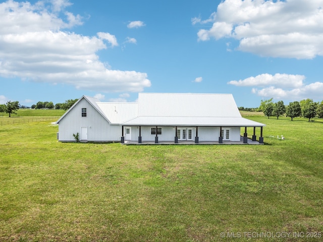 rear view of property featuring a lawn, french doors, and metal roof