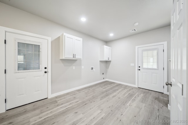 washroom featuring electric dryer hookup, light wood-type flooring, washer hookup, cabinet space, and baseboards
