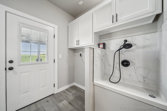 washroom with light wood finished floors, baseboards, electric dryer hookup, and cabinet space