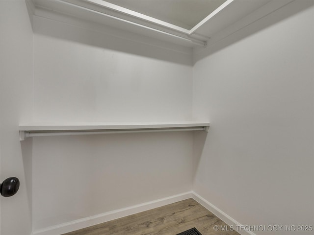 walk in closet with wood finished floors