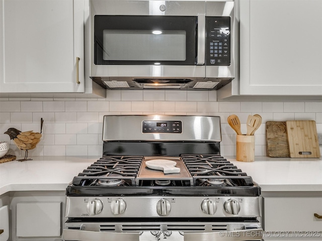 kitchen featuring light countertops, appliances with stainless steel finishes, decorative backsplash, and white cabinetry