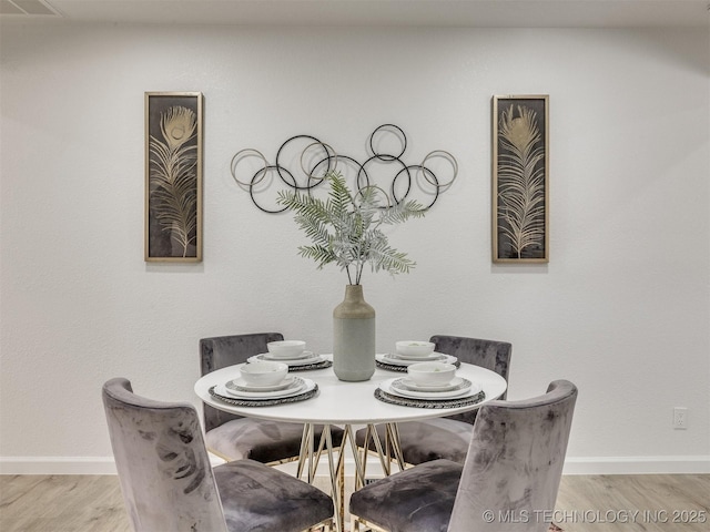 dining space with baseboards and wood finished floors