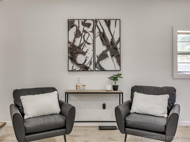 living area with visible vents and wood finished floors