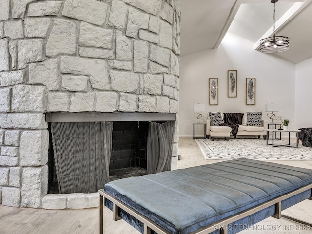 living room with an inviting chandelier, a stone fireplace, vaulted ceiling, and wood finished floors