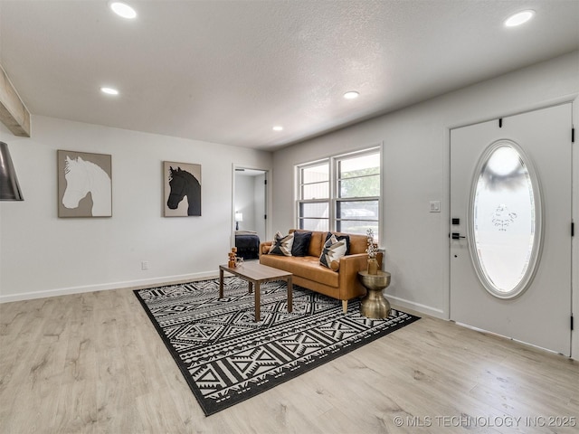 living room with a textured ceiling, wood finished floors, recessed lighting, and baseboards