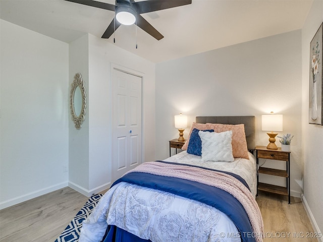 bedroom with a closet, a ceiling fan, light wood-style flooring, and baseboards
