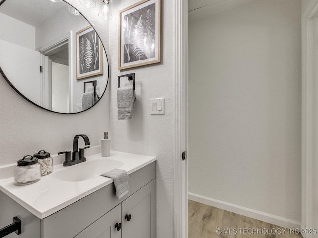 bathroom with baseboards, wood finished floors, and vanity