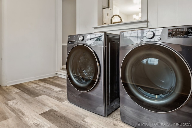 washroom featuring laundry area, washing machine and dryer, and light wood-type flooring