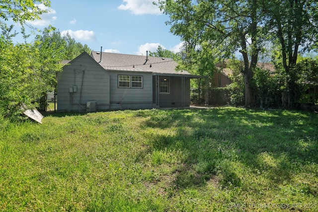 back of house with a yard, crawl space, and roof with shingles