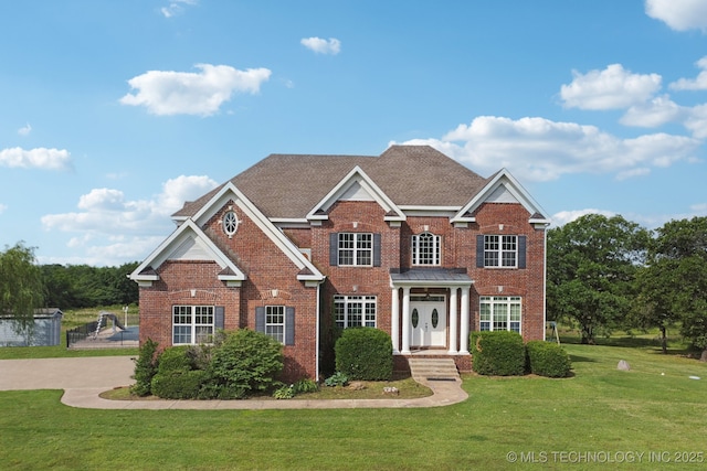 view of front of house featuring a front lawn, fence, and brick siding