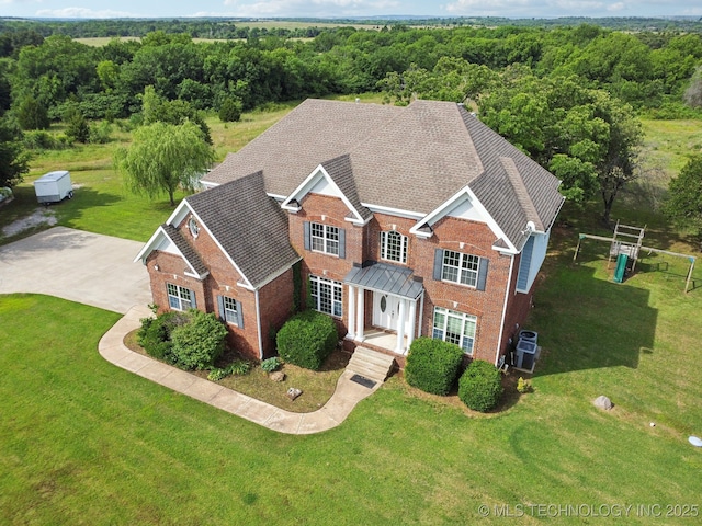 view of front of property with a front yard, a view of trees, and brick siding