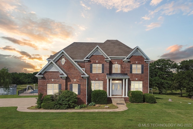 view of front facade with fence, a front lawn, and brick siding