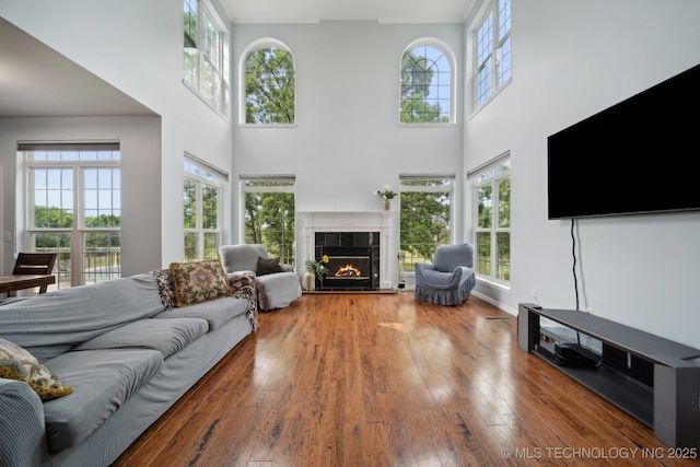 living room featuring a tile fireplace, hardwood / wood-style floors, and a high ceiling