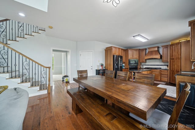 dining space featuring stairway, hardwood / wood-style flooring, and baseboards