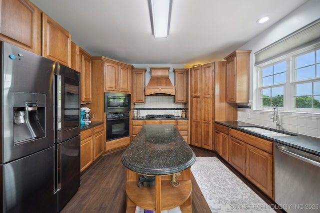 kitchen with custom exhaust hood, black appliances, a sink, and tasteful backsplash