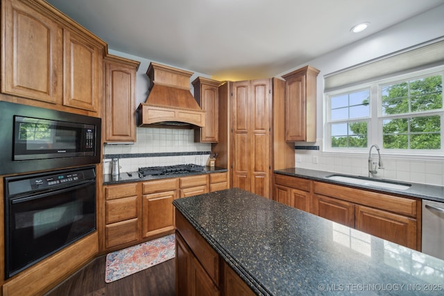 kitchen with a sink, custom exhaust hood, black appliances, backsplash, and wood finished floors