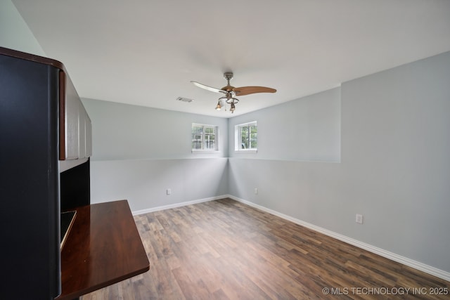 interior space featuring a ceiling fan, visible vents, wood finished floors, and baseboards