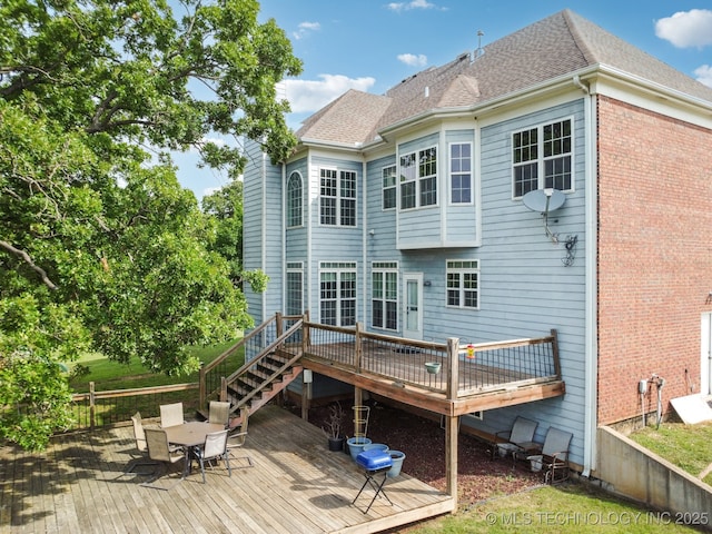 rear view of property featuring a wooden deck, outdoor dining space, and roof with shingles