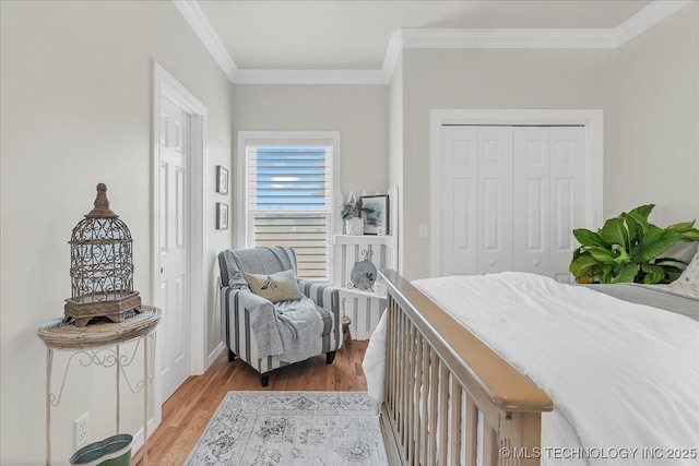 bedroom with crown molding, baseboards, a closet, and light wood finished floors