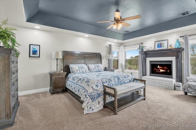 bedroom with visible vents, a fireplace, baseboards, a raised ceiling, and carpet flooring