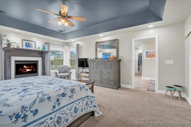 carpeted bedroom with visible vents, a fireplace, baseboards, recessed lighting, and a tray ceiling