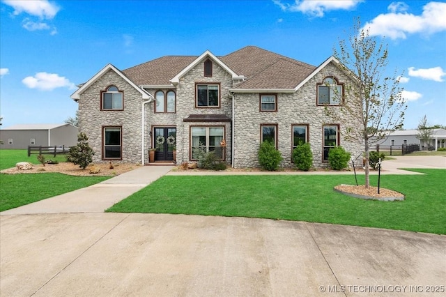 view of front facade featuring a front yard, fence, and stone siding