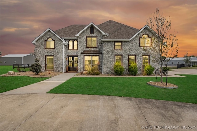 view of front of property featuring french doors, a yard, and stone siding