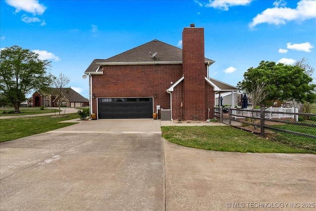 view of side of property with fence, a garage, a chimney, concrete driveway, and a yard