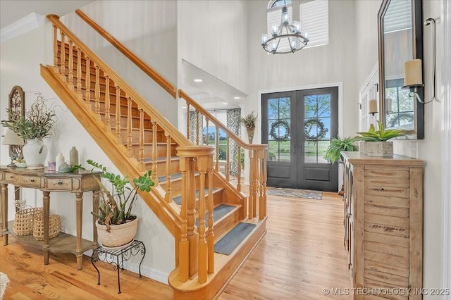 foyer entrance with stairs, a high ceiling, a notable chandelier, and wood finished floors