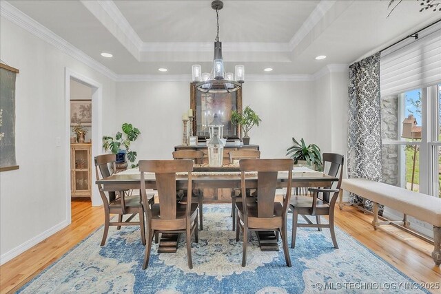 dining room with crown molding, wood finished floors, a raised ceiling, baseboards, and an inviting chandelier