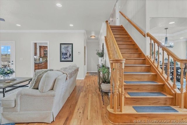 staircase with a notable chandelier, recessed lighting, baseboards, wood finished floors, and ornamental molding