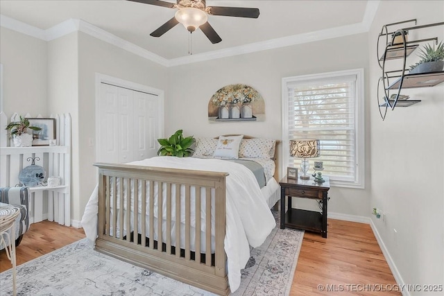bedroom featuring baseboards, ornamental molding, a closet, and wood finished floors