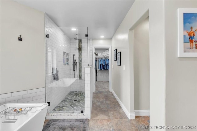 full bathroom with recessed lighting, a freestanding bath, a spacious closet, and a stall shower