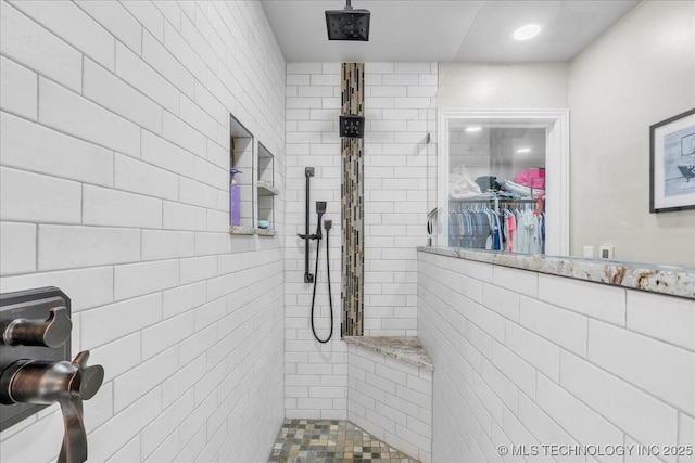full bath featuring recessed lighting, tile walls, a tile shower, and a walk in closet