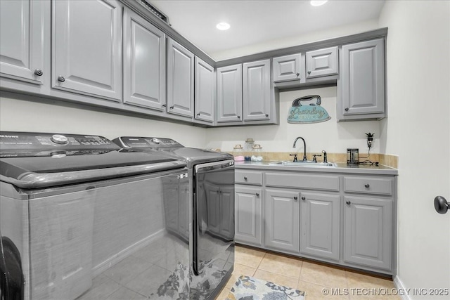 laundry area featuring cabinet space, a sink, light tile patterned floors, recessed lighting, and washer and clothes dryer