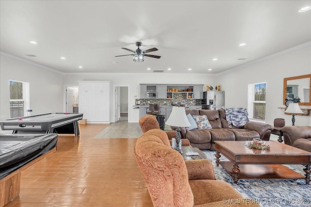 living area with recessed lighting, a ceiling fan, crown molding, and light wood-type flooring