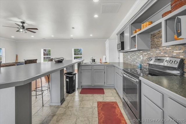 kitchen with decorative backsplash, visible vents, appliances with stainless steel finishes, a peninsula, and a breakfast bar