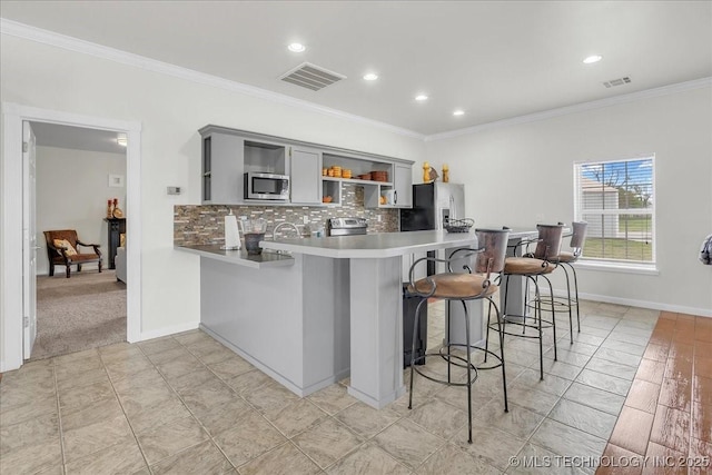 kitchen featuring crown molding, open shelves, appliances with stainless steel finishes, gray cabinets, and visible vents