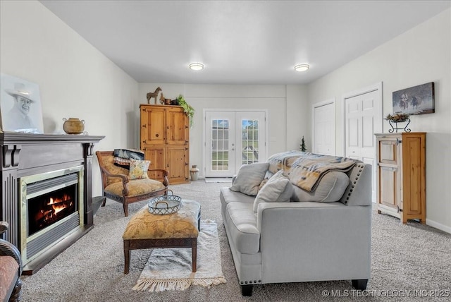 living room with a lit fireplace, baseboards, light colored carpet, and french doors