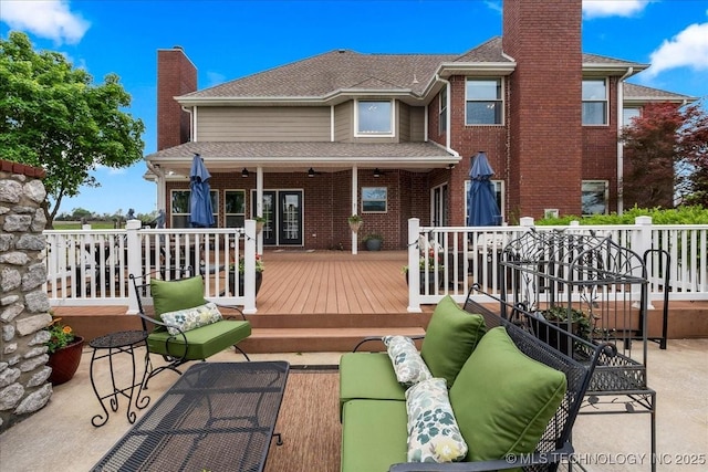 rear view of house featuring outdoor lounge area, a wooden deck, a chimney, and roof with shingles