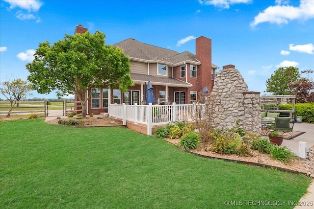 back of house with fence, brick siding, a chimney, a patio, and a yard