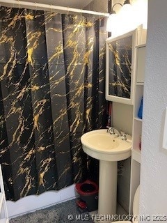 full bath with curtained shower, toilet, and a textured wall