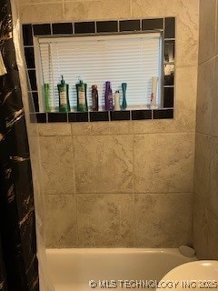 bathroom with shower / bath combo and toilet