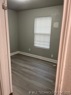spare room featuring wood finished floors and baseboards