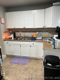 kitchen with a sink, white cabinets, and backsplash