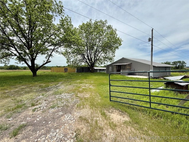 view of yard featuring a pole building, fence, and an outbuilding