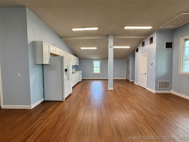 basement featuring baseboards, visible vents, white refrigerator with ice dispenser, and wood finished floors