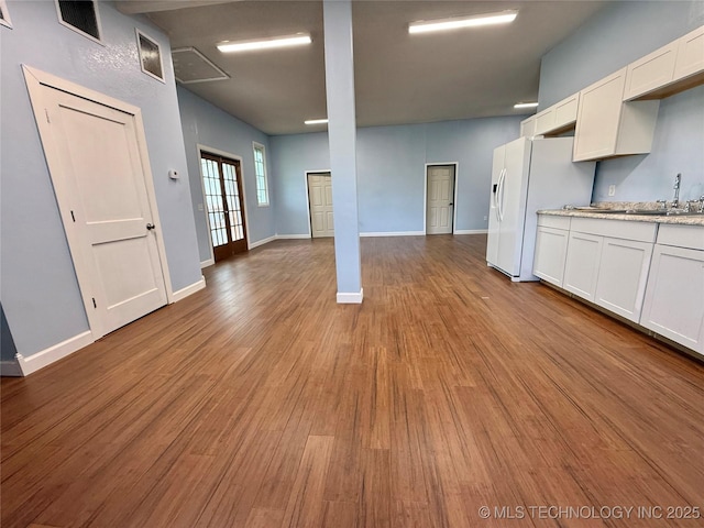 unfurnished living room with a sink, baseboards, wood finished floors, and visible vents