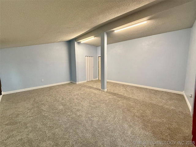 finished below grade area featuring baseboards, carpet flooring, and a textured ceiling