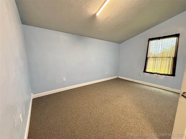 spare room featuring baseboards, vaulted ceiling, dark colored carpet, and a textured ceiling